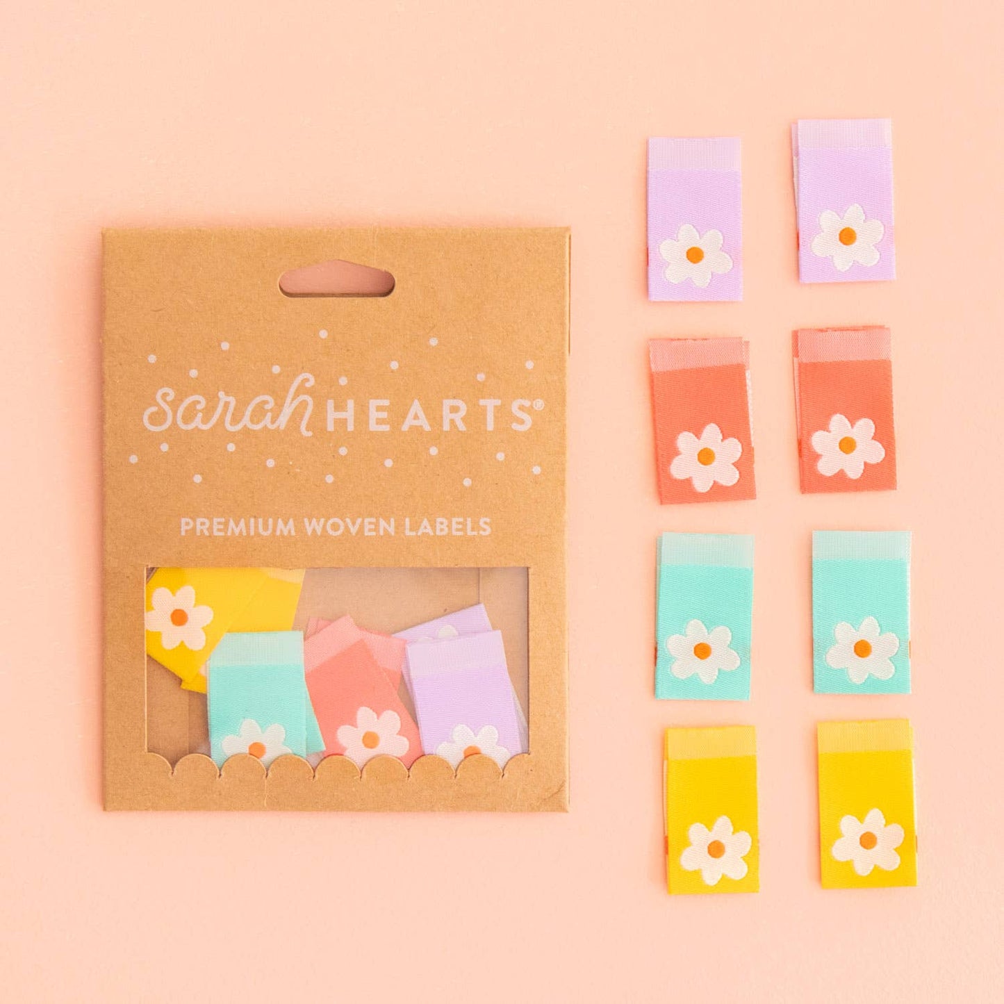 Kleding labels in verschillende pastelkleuren met een madeliefje er op van Sarah Hearts.