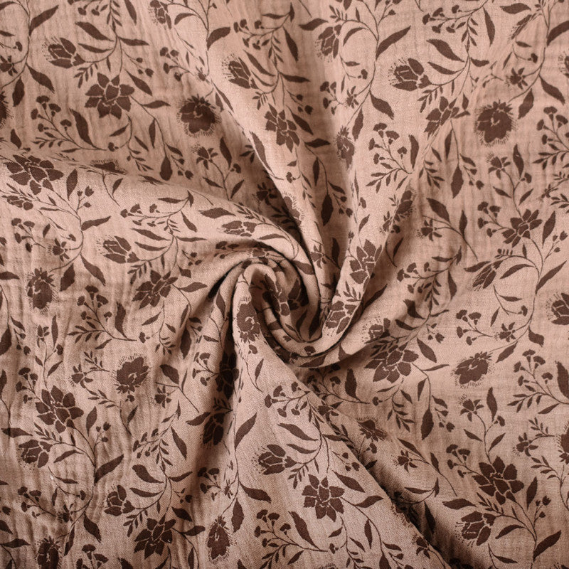 Mocca kleurig hydrofiel stof met bruine bloemen en planten erop, voor het maken van kleding, zoals een jurk of rok of zomerse broek.
