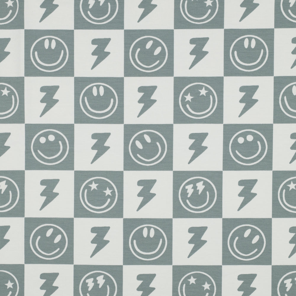 Tricot met blokjes en smiley's in de kleuren gebroken wit met salie groen.