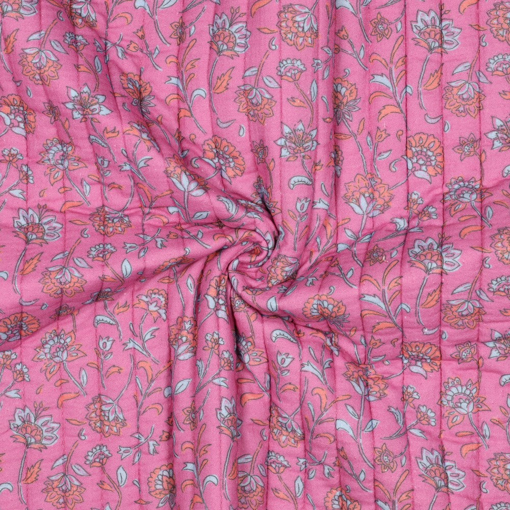 Gewatteerde doorgestikte double gauze die aan twee kanten draagbaar is in de kleuren fuchsia en lichtblauw met bloemetjes.