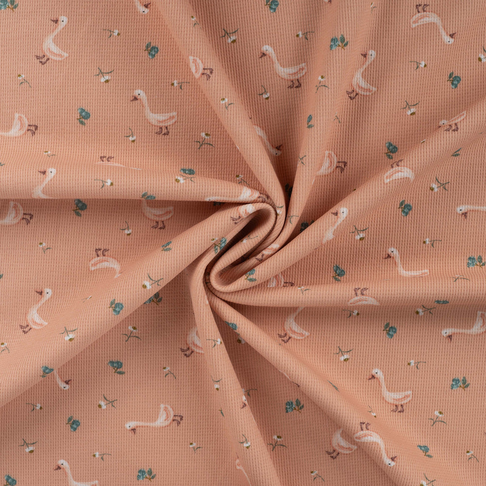 Wafeltricot stof zalmroze met gansjes.