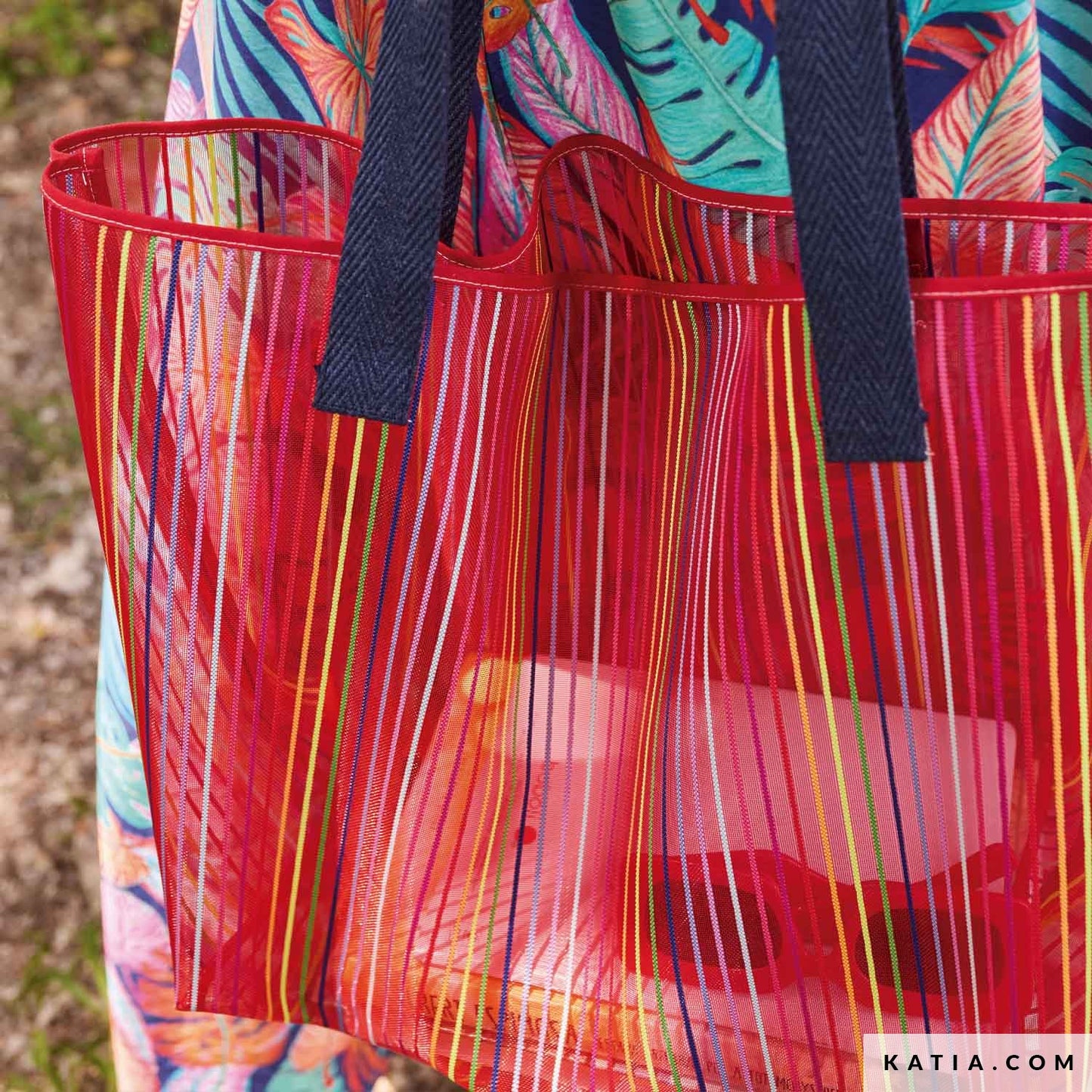 Strandtas gemaakt van koraal kleurige mesh stof multicolor strepen.