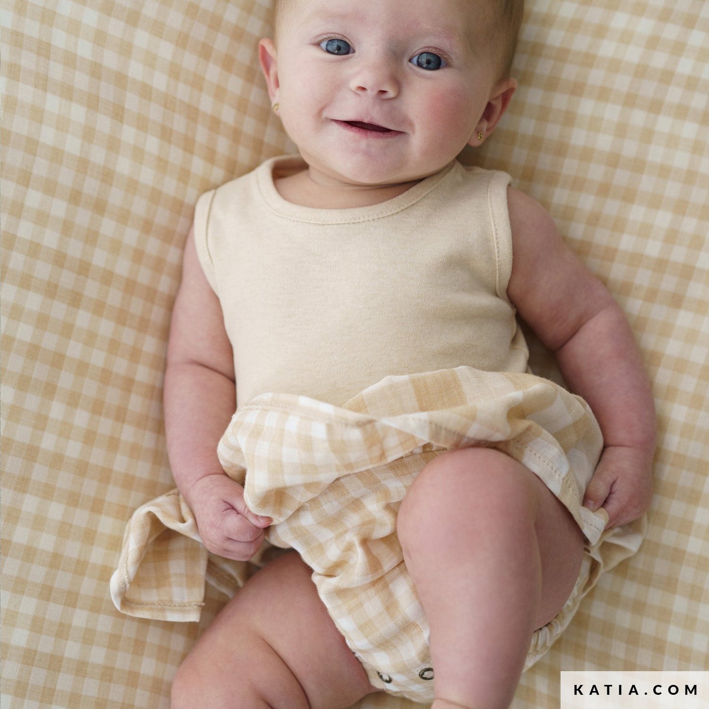Babypakje gemaakt van dubbelzijdige biologisch katoenen double gauze in ecru met lichtbruine blokjes.
