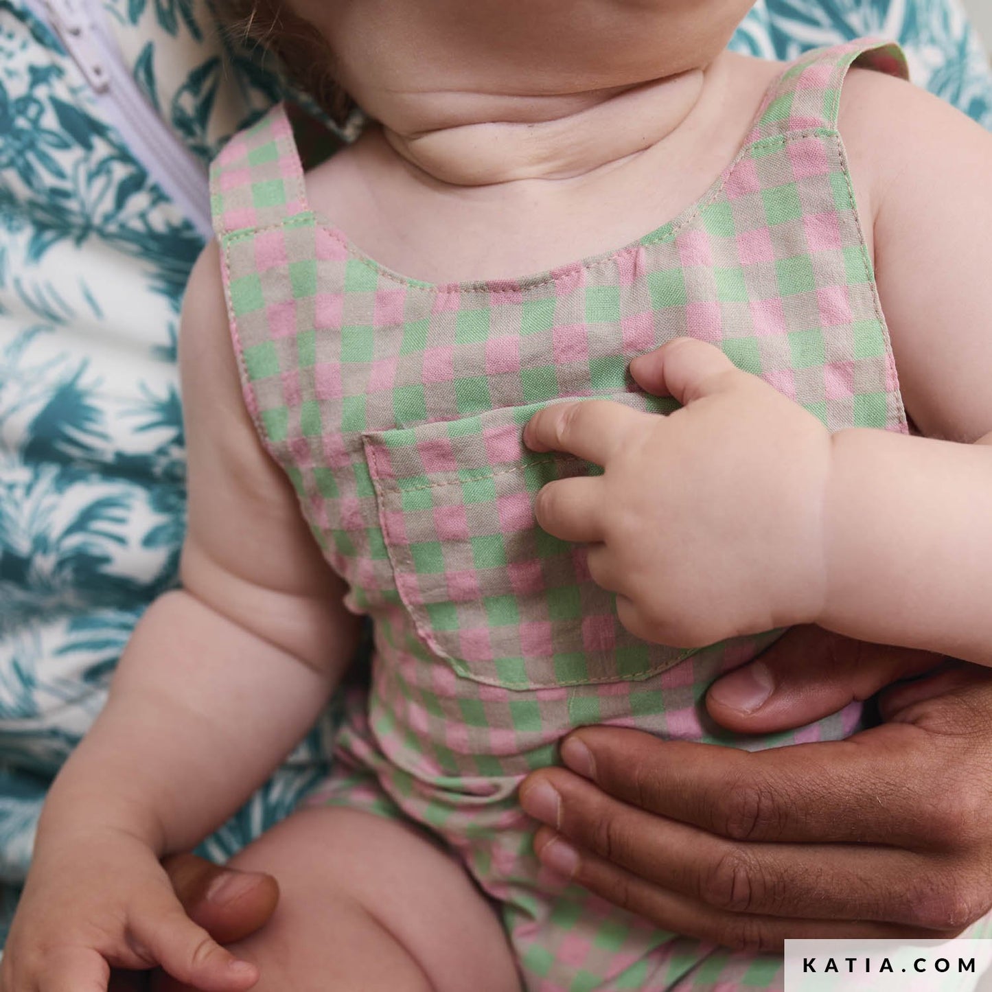 Babypakje gemaakt  van ruitjes stof in de kleuren roze en groen.