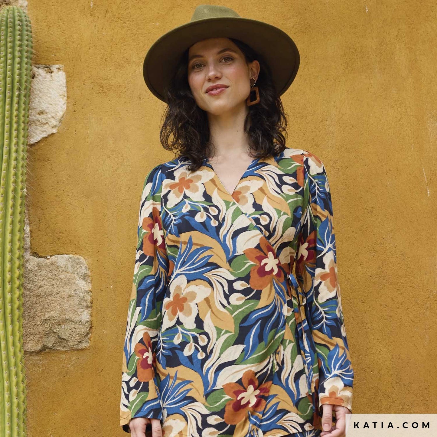Jurk gemaakt van viscose stof met botanische print van blauwe, oranje, gele en groene bloemen en bladeren.
