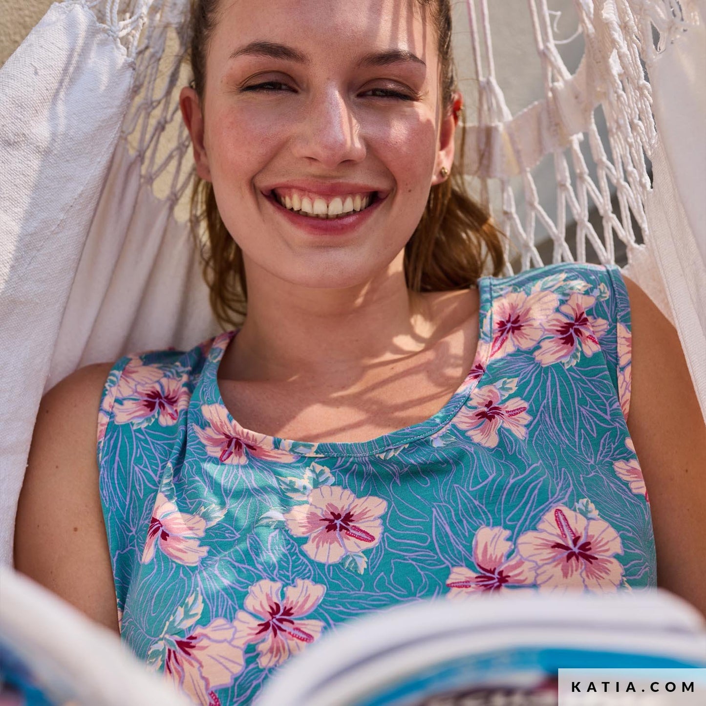 Jurk gemaakt van turquoise viscose jersey stof met grote licht roze bloemen en lila bladeren.